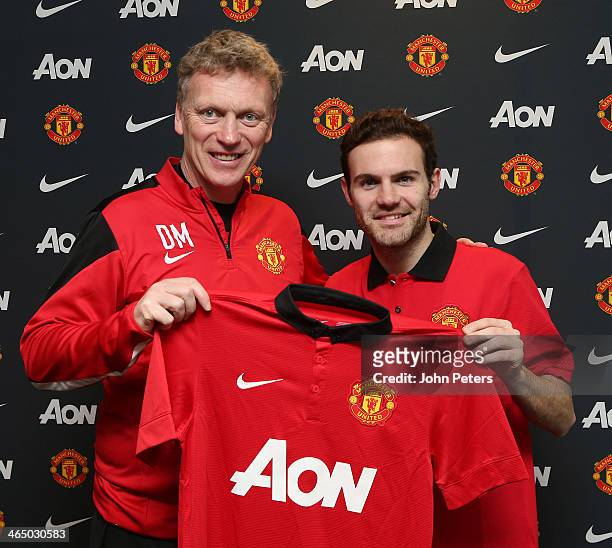 Juan Mata of Manchester United poses with Manchester United Manager David Moyes and a Manchester United shirt after signing his contract with the...
