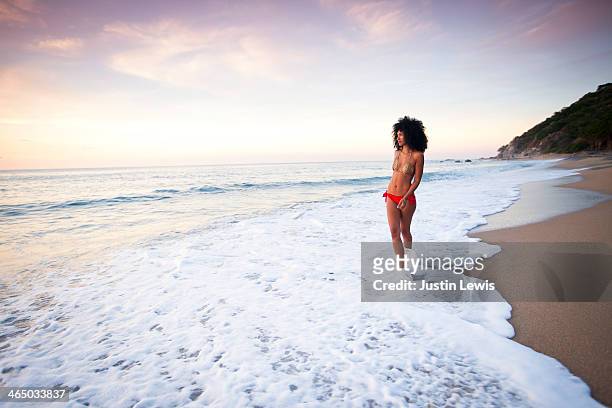 girl in bikini walking in ocean water at sunset - beautiful black women in bathing suits stock pictures, royalty-free photos & images