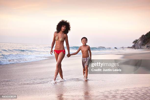 mother & son walking in sand at beach during sunet - com os pés na água imagens e fotografias de stock