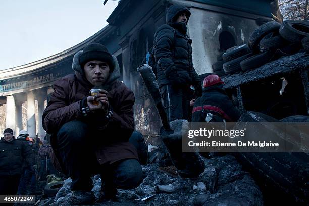 Anti government protesters watch the riot police line from behind a bariccade during a standoff on Hrushevskoho street during a standoff with police...