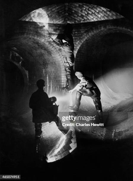 Sewermen inspecting the wall of a sewer under the streets of Clapham in south London, April 1950. Original publication: Picture Post - 5007 - Under...