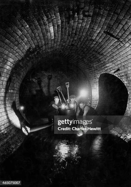 Sewermen removing a trolley loaded with silt deposits from a London sewer, April 1950. Original publication: Picture Post - 5007 - Under London -...