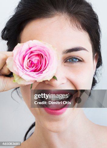 Young woman holding rose to her face, laughing Young woman holding rose to her face, laughing