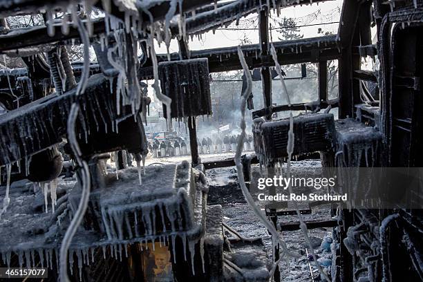 Police lines are seen through the wreckage of a bus on Grushevskogo Street on January 26, 2013 in Kiev, Ukraine. Violent protests in Ukraine continue...