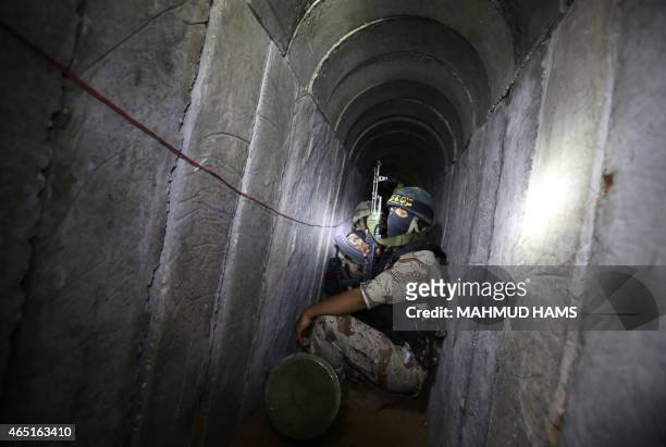 Palestinian militants from the Islamic Jihad's armed wing, the Al-Quds Brigades, squat in a tunnel, used for storing weapons, as they take part in...