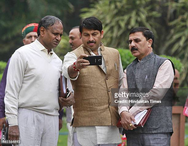 MPs Manoj Tiwari and Udit Raj looking at mobile phone after the BJP Parliamentary Board meeting during budget session at Parliament house on March 3,...