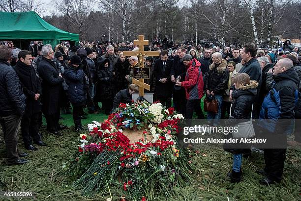 People place flowers near the cross at the grave of Russian opposition leader Boris Nemtsov at Troyekurovskoye Cemetary on March 3, 2015 in Moscow,...