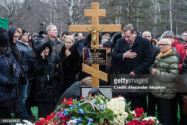People place flowers near the cross at the grave of Russian opposition leader Boris Nemtsov at Troyekurovskoye Cemetary on March 3, 2015 in Moscow,...
