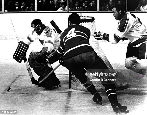 Jean Beliveau of the Montreal Canadiens goes after the puck as his former teammates goalie Jacques Plante and Doug Harvey of the St. Louis Blues...
