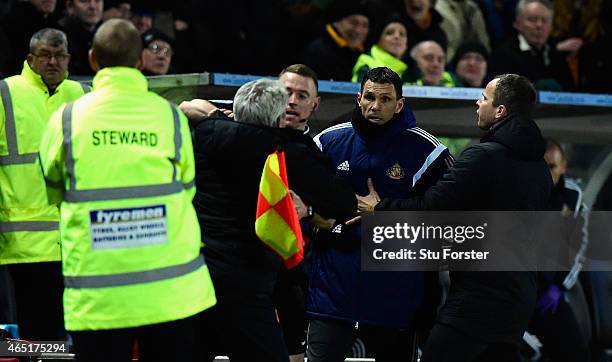 Hull manager Steve Bruce is held back by the assistant referee as he and Sunderland manager Gus Poyet argue after Poyet is sent to the stand during...