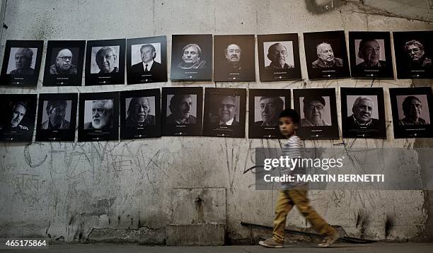 Boy walks next to pictures on display in a now gallery that once -during Augusto Pinochet's dictatorship - served as a jail for prisoners, in the...