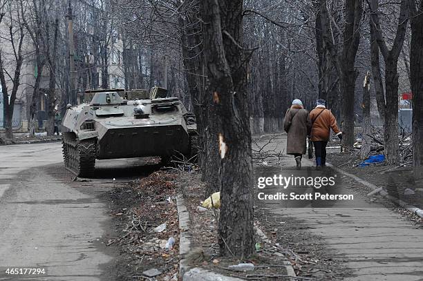 Two Ukrainian women walk past a wrecked armored personnel carrier as Debaltseve copes with the aftermath of a siege and then capture by...