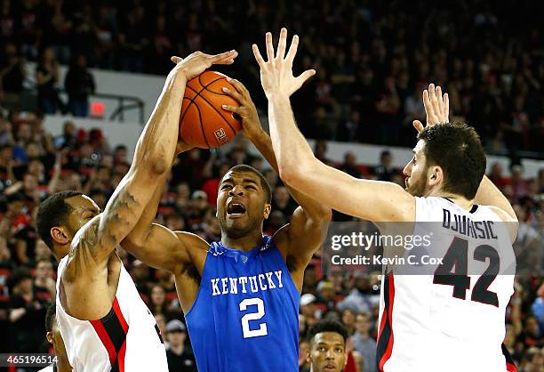 Aaron Harrison of the Kentucky Wildcats draws a foul as he drives between Marcus Thornton and Nemanja Djurisic of the Georgia Bulldogs at Stegeman...