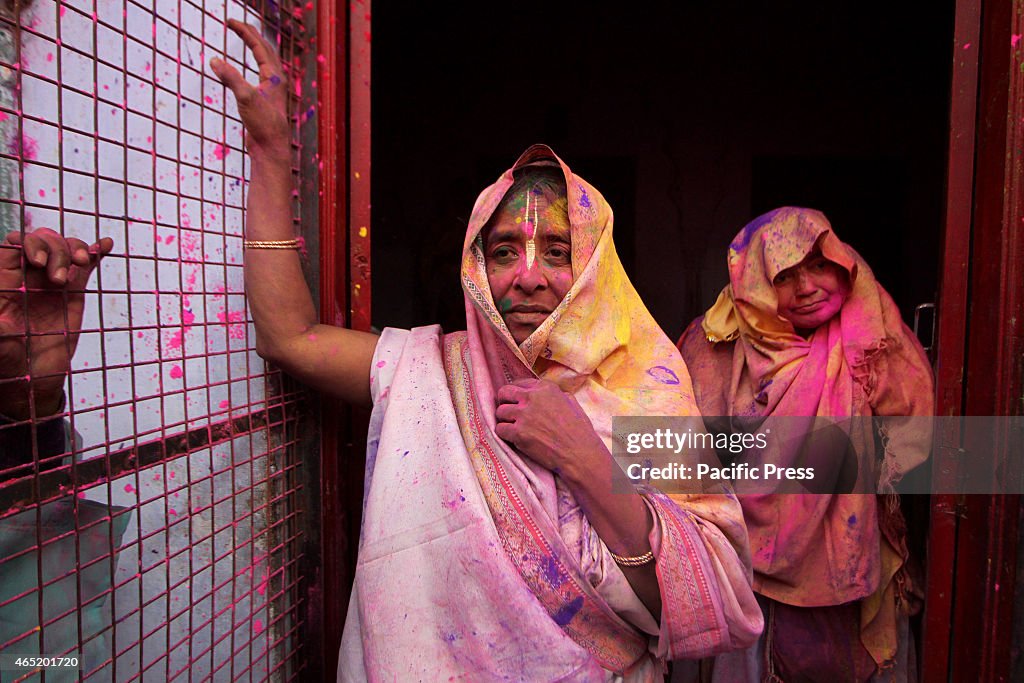 Indian Hindu widows play with colored powder as a part of...