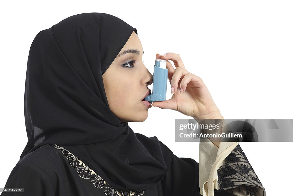 Saudi arabian woman breathing from an asthma inhaler
