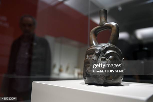 Visitor looks at a cerimonial container representing a human face morphing into that of a feline during an exhibition of Peruvian Mochica art on...