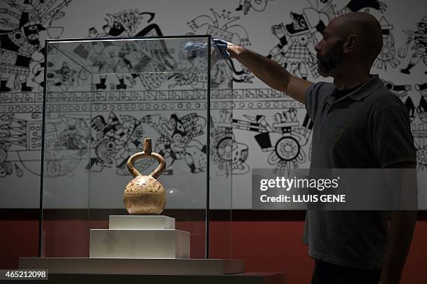 Worker cleans the glass case housing a the ceremonial bottle illustrated with a sacrificial ceremony representing captive warriors during an...