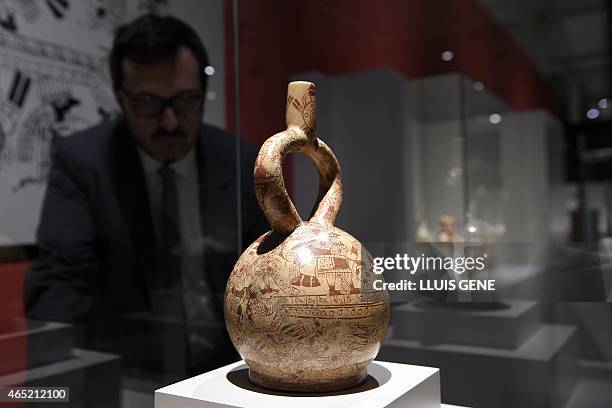 Visitor looks the ceremonial bottle illustrated with a sacrificial ceremony representing captive warriors during an exhibition of Peruvian Mochica...