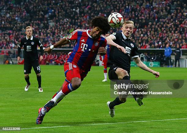 Dante of FC Bayern Muenchen heads the ball under the pressure of Maximilian Sauer of Eintracht Braunschweig during the round of 16 DFB Cup match...