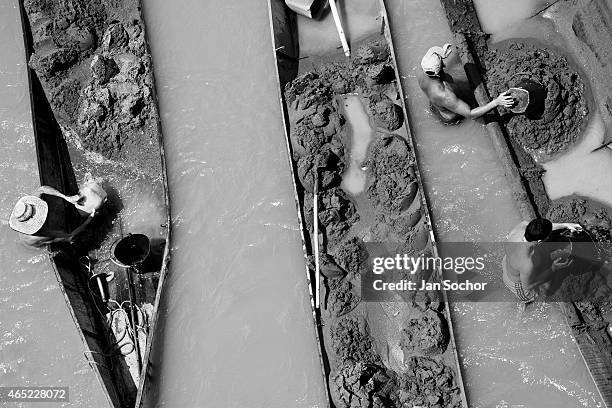 Colombian sand miners unload buckets full of sand onto their boats anchored in the middle of the river La Vieja on February 08, 2013 in Cartago,...