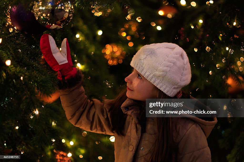 Girl standing next to a Christmas tree