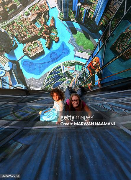 Woman and her daughter pose on a chalk 3-D artwork on March 4, 2015 near the Jumeirah Beach Residence in Dubai during the Canvas Festival, a...