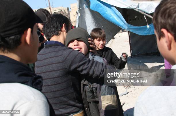 Syrian child is comforted by another youth following a reported barrel bomb strike by Syrian government forces on March 5, 2015 in the Kadi Askar...