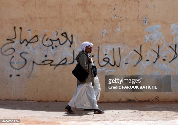 Algerians walk past a wall on which a graffiti reads in Arabic "no to hydraulic fracturing " on March 5, 2015 during a protest at Somoud Square in...