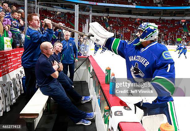 Roberto Luongo of the Vancouver Canucks hands his stick to trainer Brian Hamilton before their NHL game against the Phoenix Coyotes at Rogers Arena...