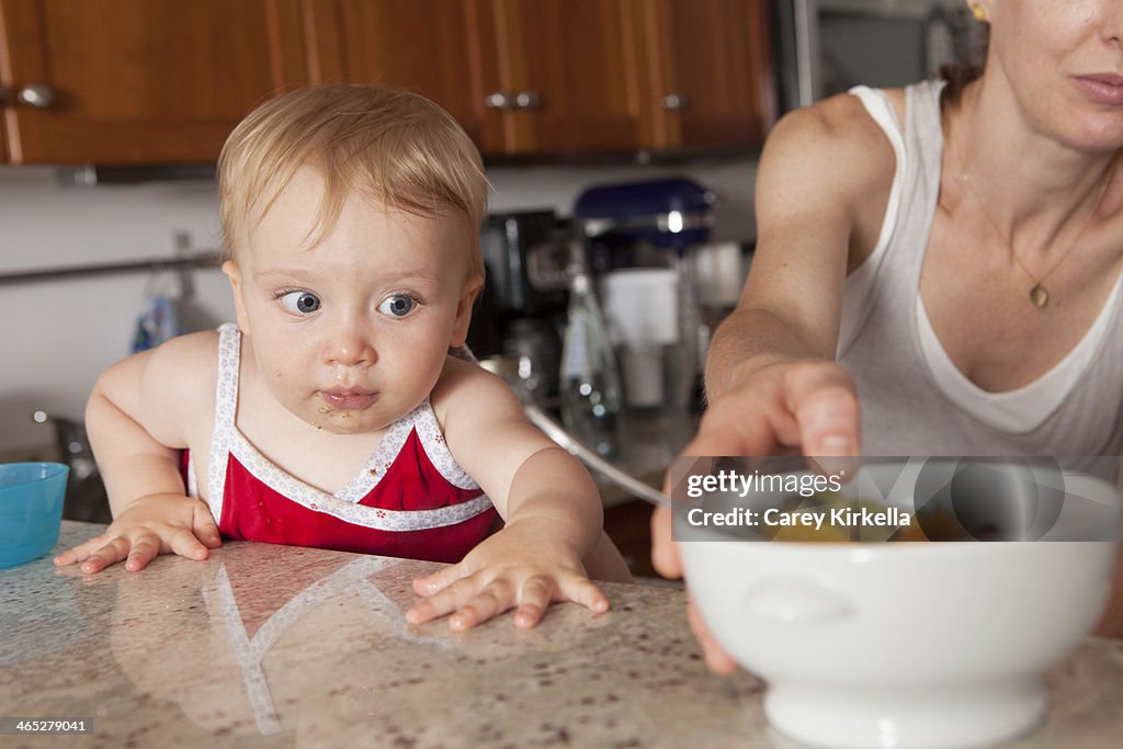 A baby about to reach for a bowl of fruit