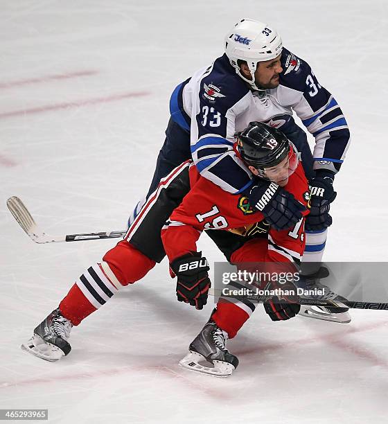 Dustin Byfuglien of the Winnipeg Jets pulls down Jonathan Toews of the Chicago Blackhawks at the United Center on January 26, 2014 in Chicago,...
