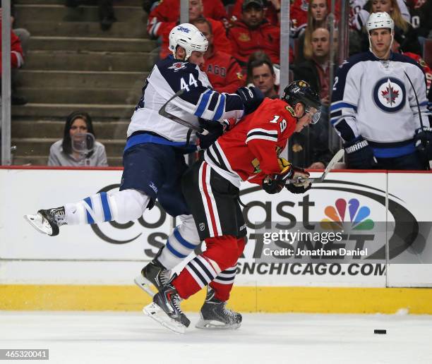 Zach Bogosian of the Winnipeg Jets jumps on the back of Jonathan Toews of the Chicago Blackhawks at the United Center on January 26, 2014 in Chicago,...