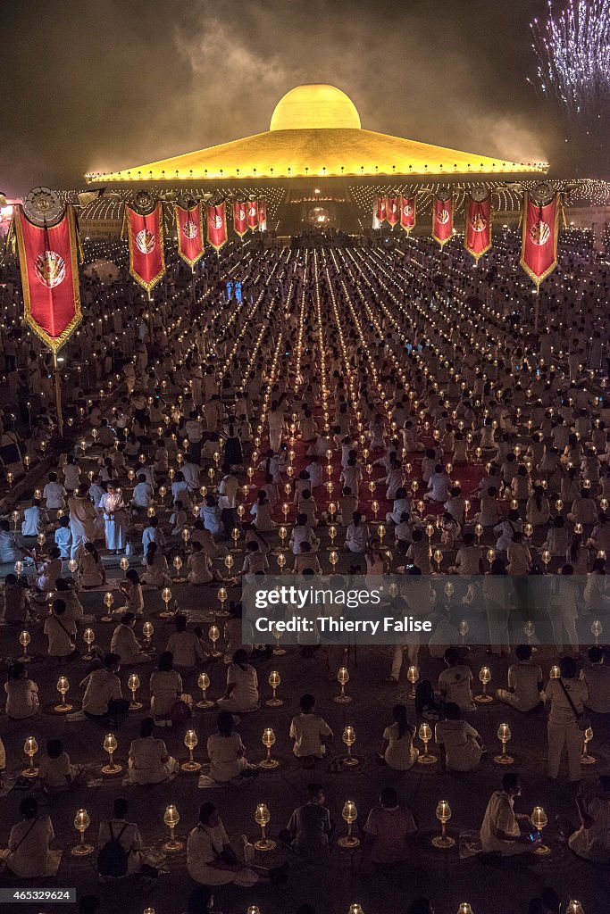 Tens of thousands of Dhammakaya temple's members sit around...