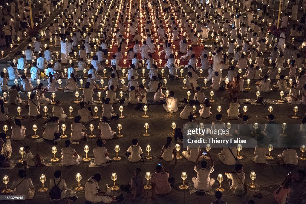 Tens of thousands of Dhammakaya temple's members sit around...