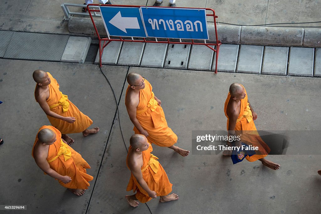 Monks from Dhammakaya temple's walk past a board in Thai...