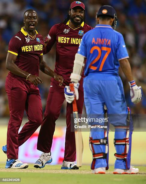 Kemar Roach and Chris Gayle of the West Indies celebrate the wicket of Ajinkya Rahane of India during the 2015 ICC Cricket World Cup match between...