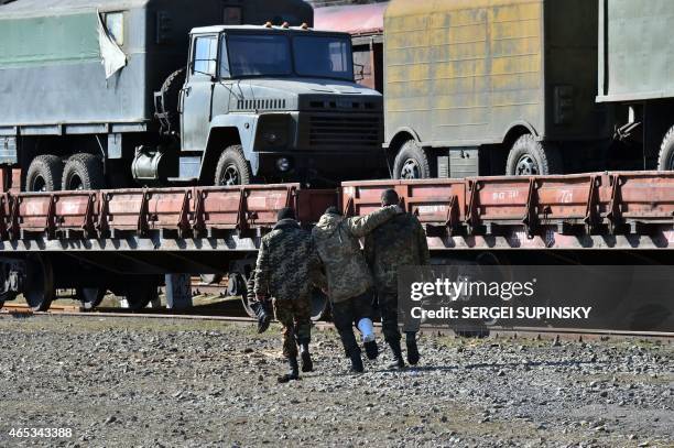 Ukrainian servicemen assist a fellow soldier during the loading of heavy weapons onto a cargo train at the railway station in the eastern Ukrainian...