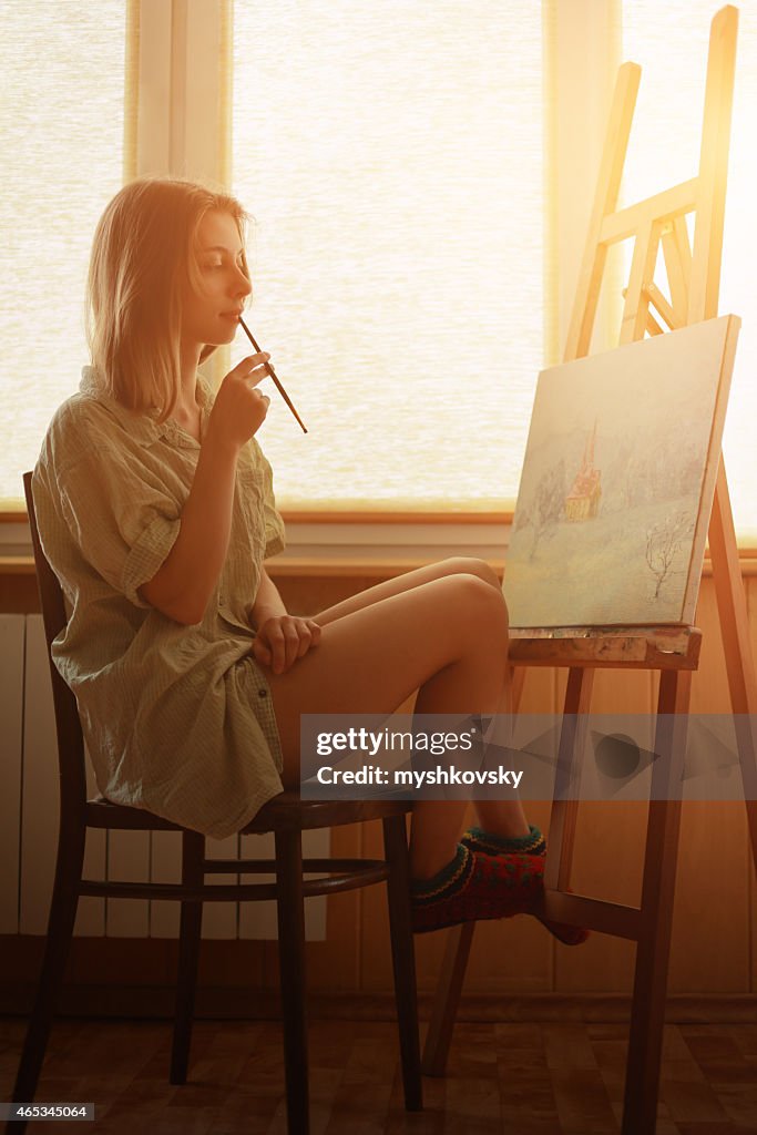 Giovane donna dipinto paesaggio vicino alla finestra