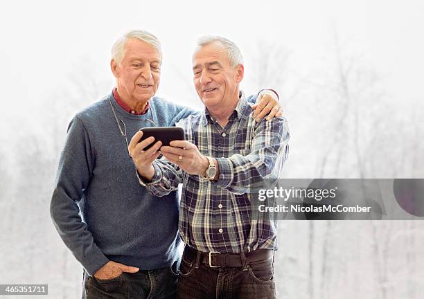 senior pareja gay tiroteo en un autorretrato con teléfono móvil - gay seniors fotografías e imágenes de stock