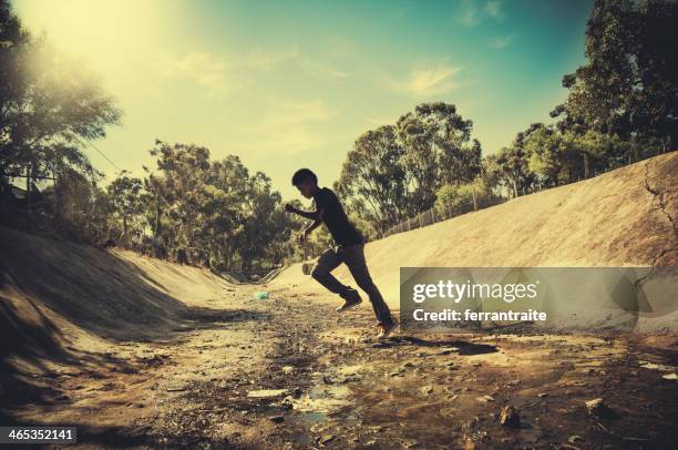 adolescent courir sur ouvert système d'écoulement des eaux - système découlement des eaux photos et images de collection