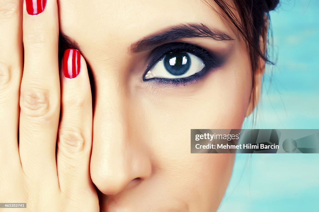 Young woman with make up on covering one eye