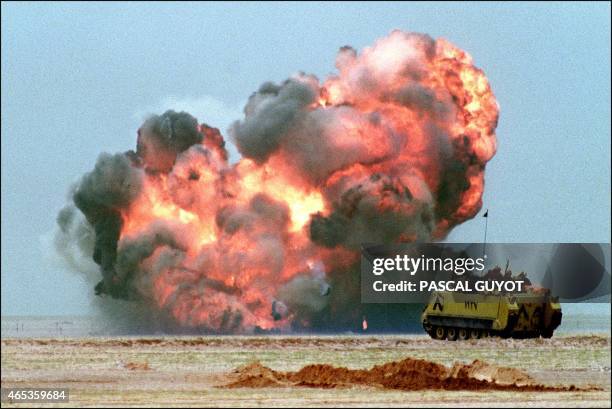 An Egyptian light armoured vehicle explodes 25 February 1991 after driving over an Iraqi mine, on the second day of the massive ground assault of the...