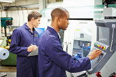 Engineer And Apprentice Using Automated Milling Machine