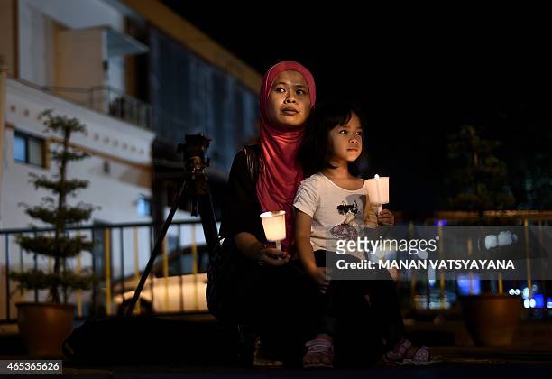 Young Malaysian girl sits in her mother's lap during a gathering to mark the one-year anniversary of the disappearance of Malaysia Airlines flight...