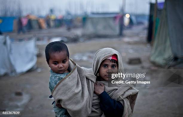 Saina holds her two-year-old brother, Nargis, in the Malakpur relief camp January 22, 2014 in the Shamli district of Uttar Pradesh, India. Riots...