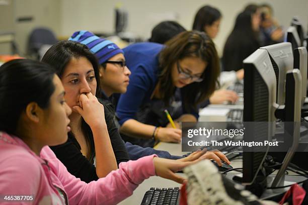Volunteer Daniela Martinez, 2nd from L, closely reads the college essay of high school student Seila, the only name she wishes to use, while...