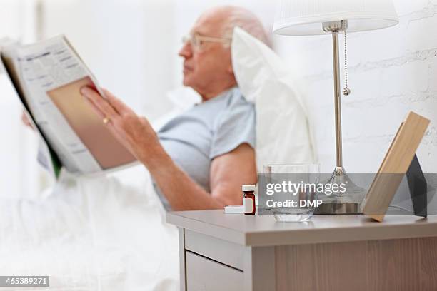 uomo anziano leggendo un quotidiano in camera da letto - tavolino di servizio foto e immagini stock