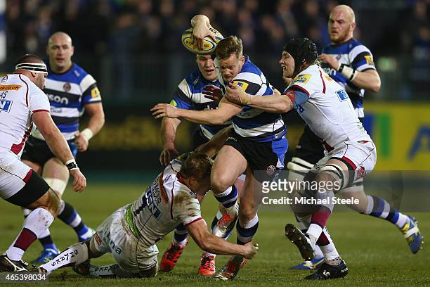 Tom Homer of Bath is held up by David Seymour and Magnus Lund of Sale during the Aviva Premiership match between Bath Rugby and Sale at the...