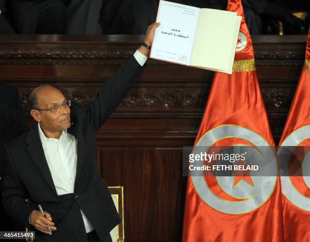 Tunisian president Moncef Marzouki shows a copy of the new constitution after its adoption on January 27, 2014 during a ceremony at the NCA in Tunis....