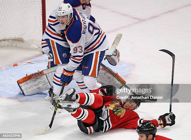 Kris Versteeg of the Chicago Blackhawks hits the ice next to Ryan Nugent-Hopkins of the Edmonton Oilers at the United Center on March 6, 2015 in...